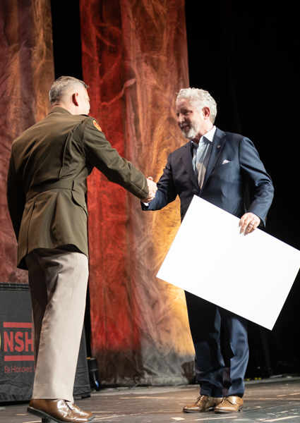 A man shaking another man's hand on stage