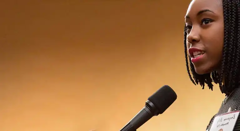 An African American Woman speaking into a microphone